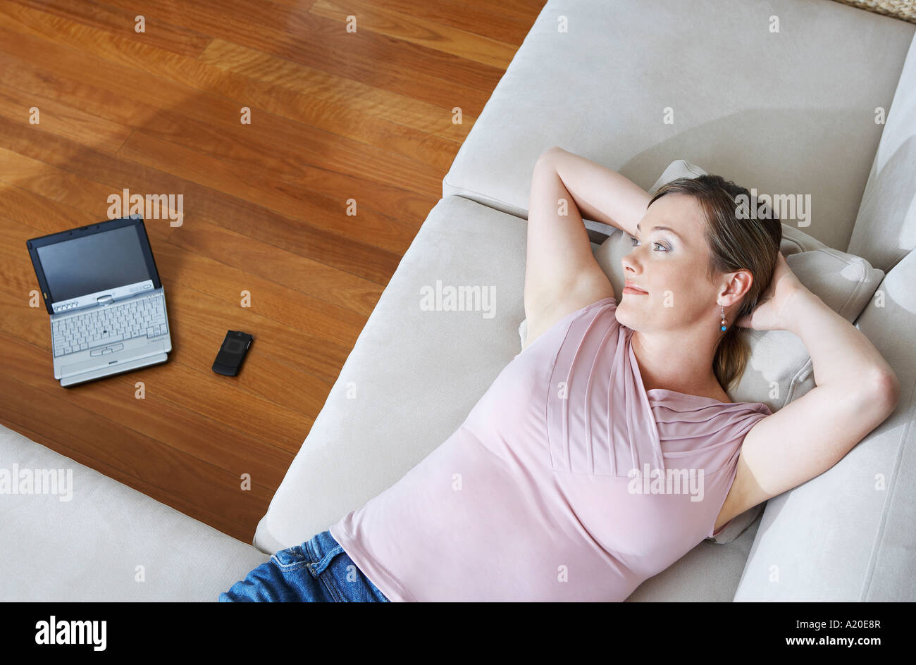 Woman lying down on couch, laptop in background, view from above Stock Photo Alamy