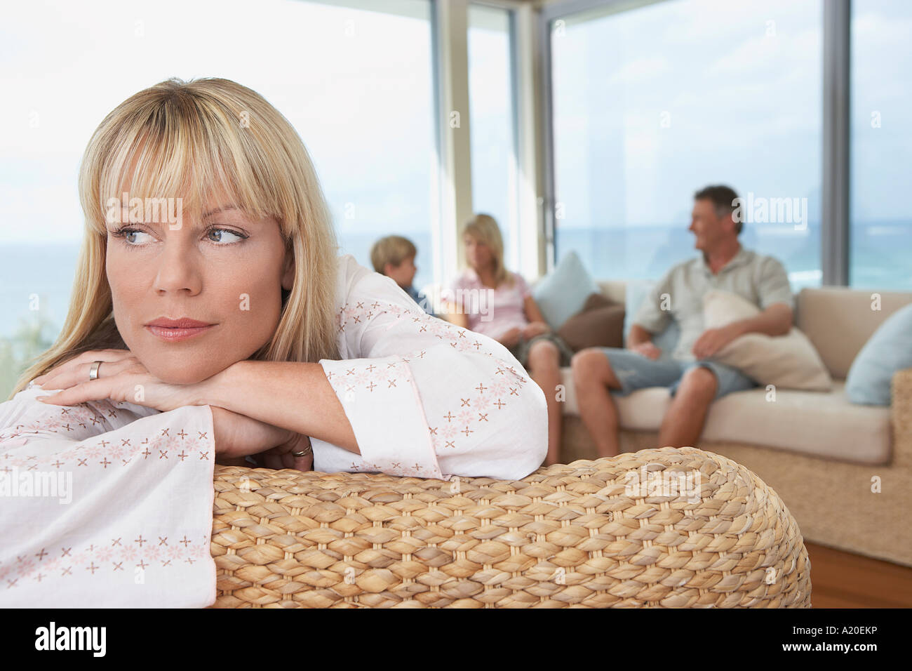 Woman lying, arms crossed, over back of chair, family in background