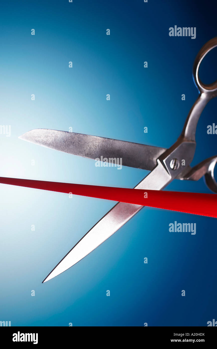 Scissors cutting red ribbon in studio Stock Photo