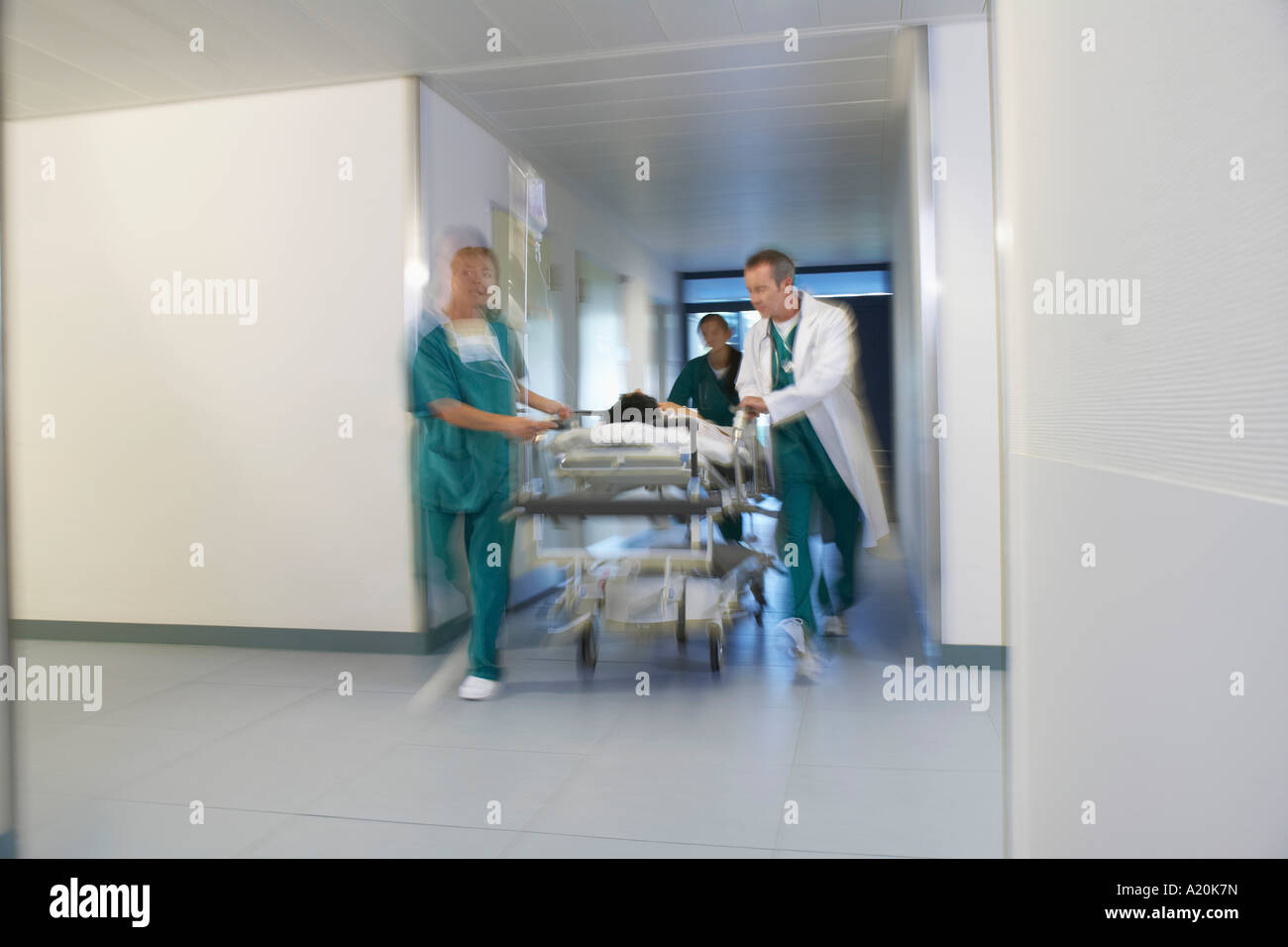 Doctors running Patient on gurney through hospital corridor, motion