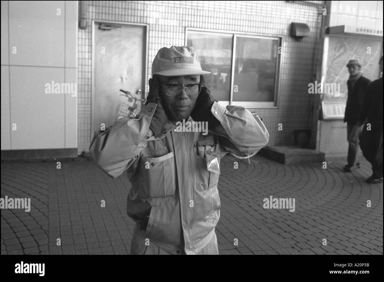 worker covers his ears with his hands to block the noise of a passig anti-Iraq war demonstration, Tokyo, Japan Stock Photo