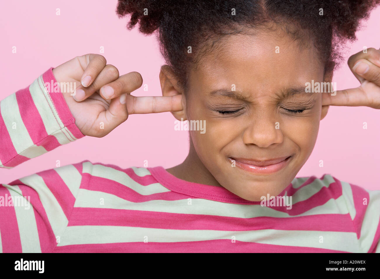 Girl with eyes closed, putting Fingers in Ears, close-up Stock Photo