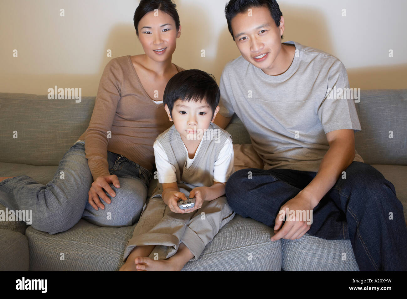 Couple sitting on sofa, Watching Television while son is using remote control Stock Photo