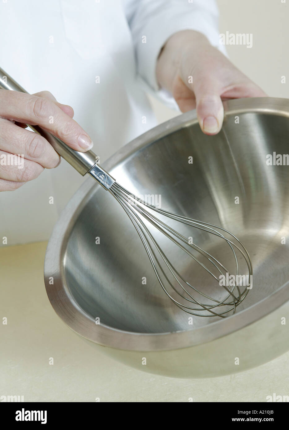 Detail image of hands whisking in empty silver clinical chemical bowl