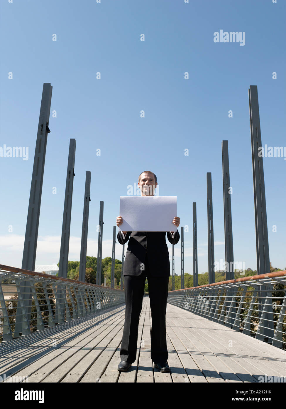 Young business man standing on bridge holding papers Stock Photo