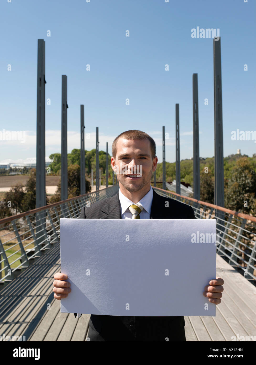 Young business man standing on bridge holding papers Stock Photo