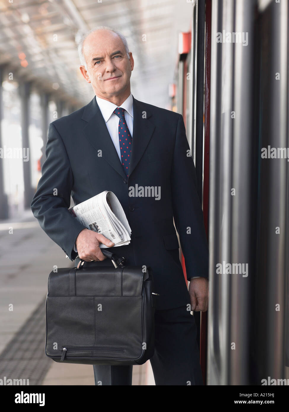 Mature Businessman holding briefcase and newspaper, standing outside