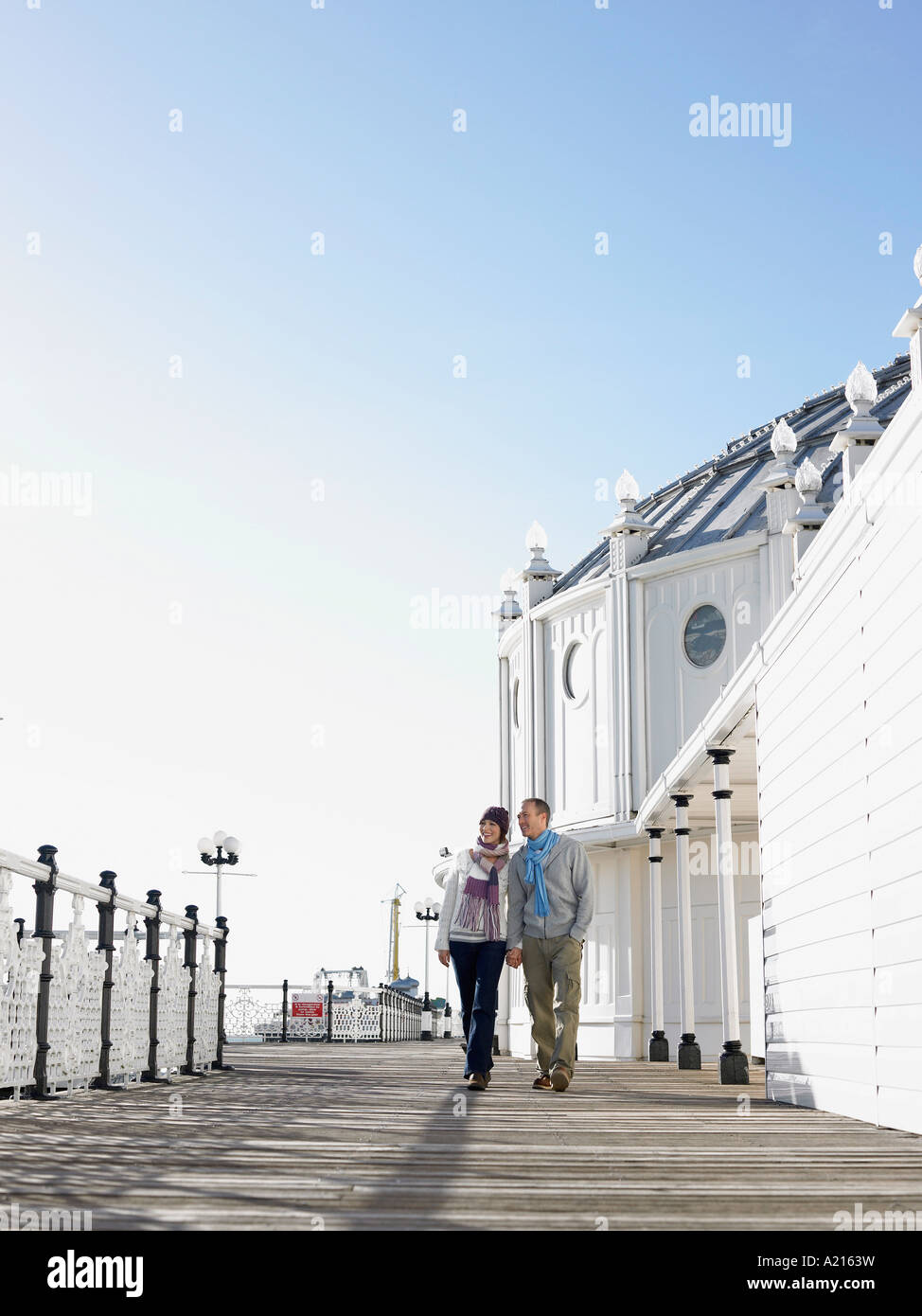 Couple holding hands, walking along pier Stock Photo