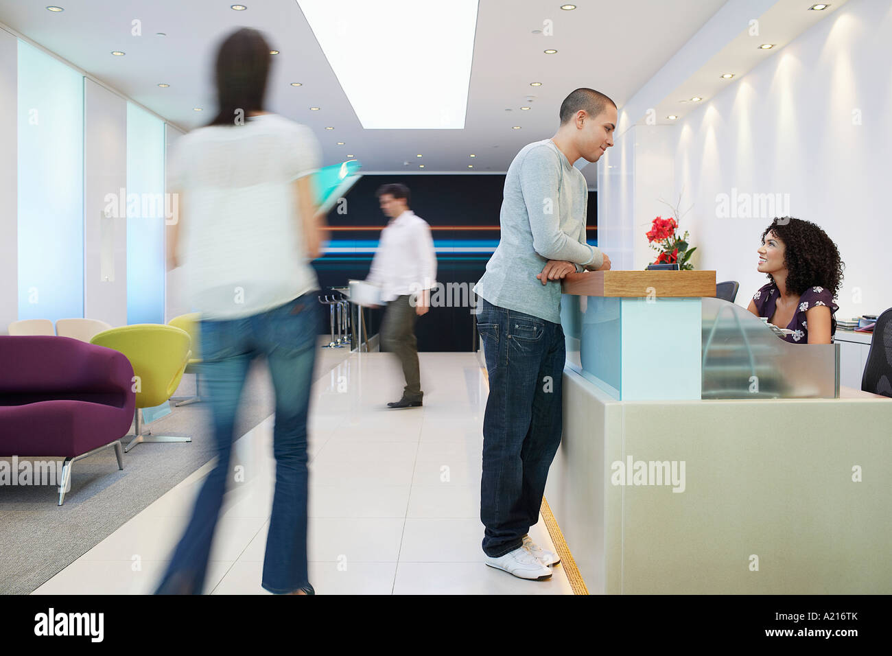 Man standing at reception desk, Talking to Receptionist, side view
