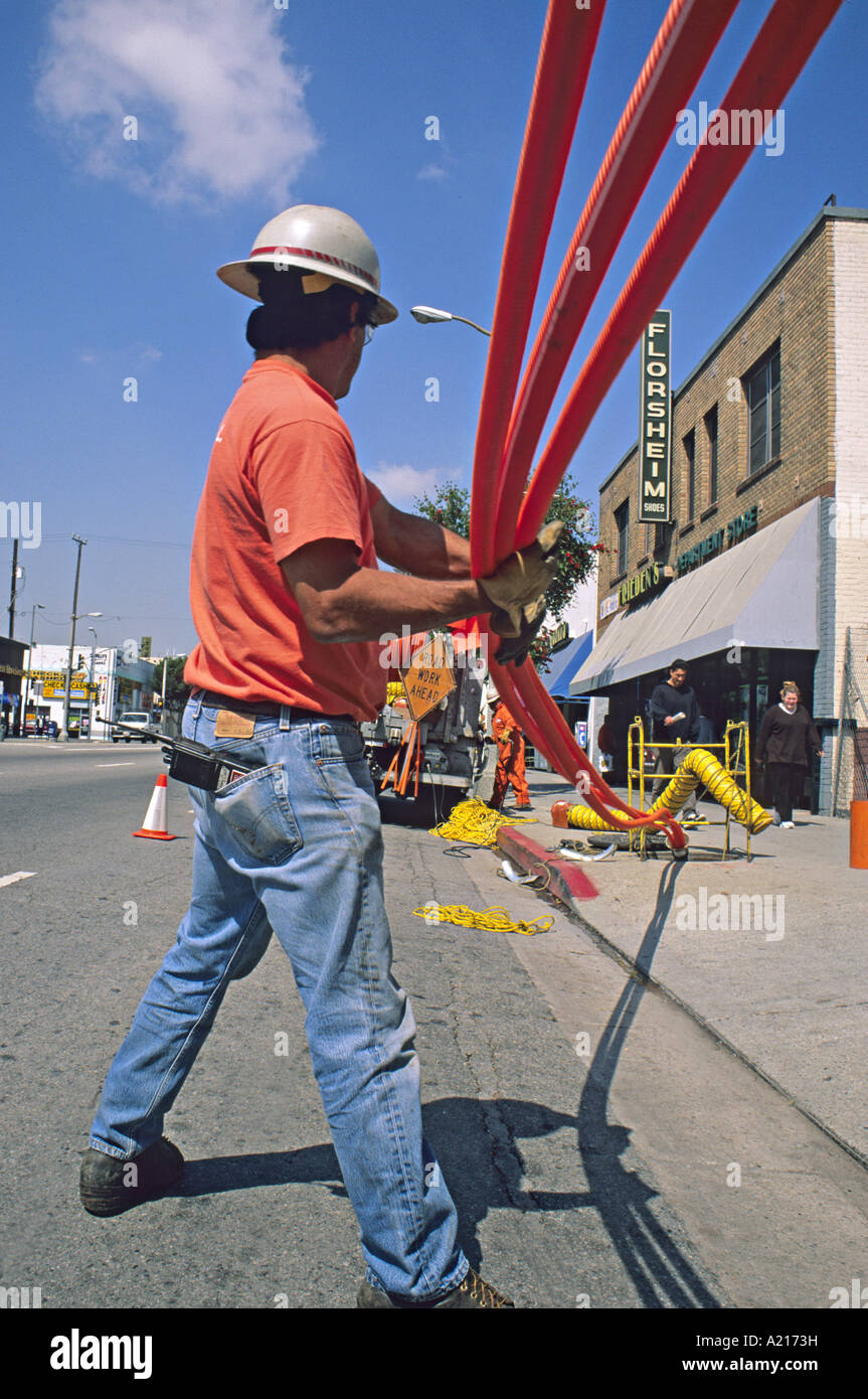 technicians install fiber optic conduit under street Los Angeles Stock Photo