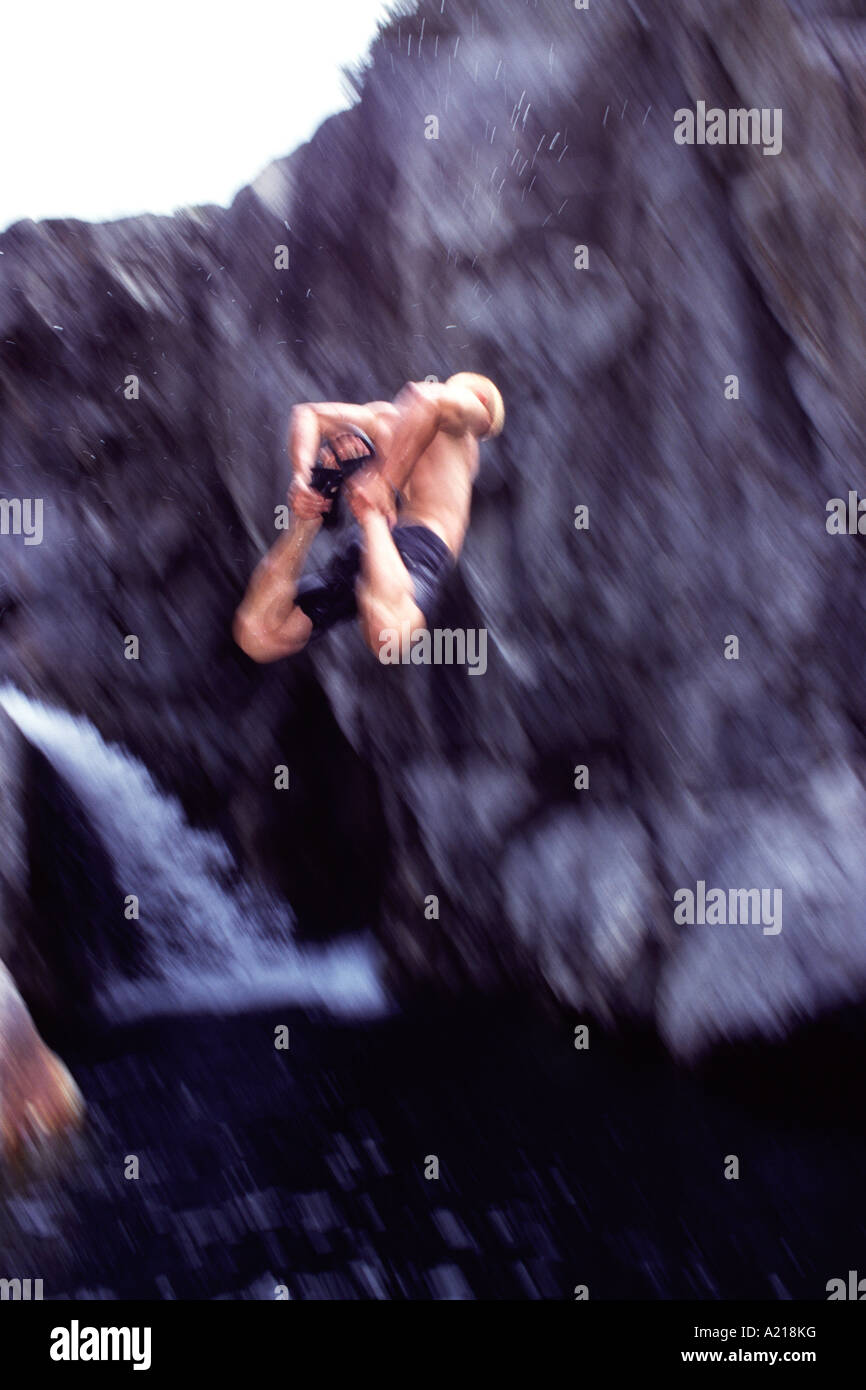 A blurry photo of a man jumping off a cliff into water on the South