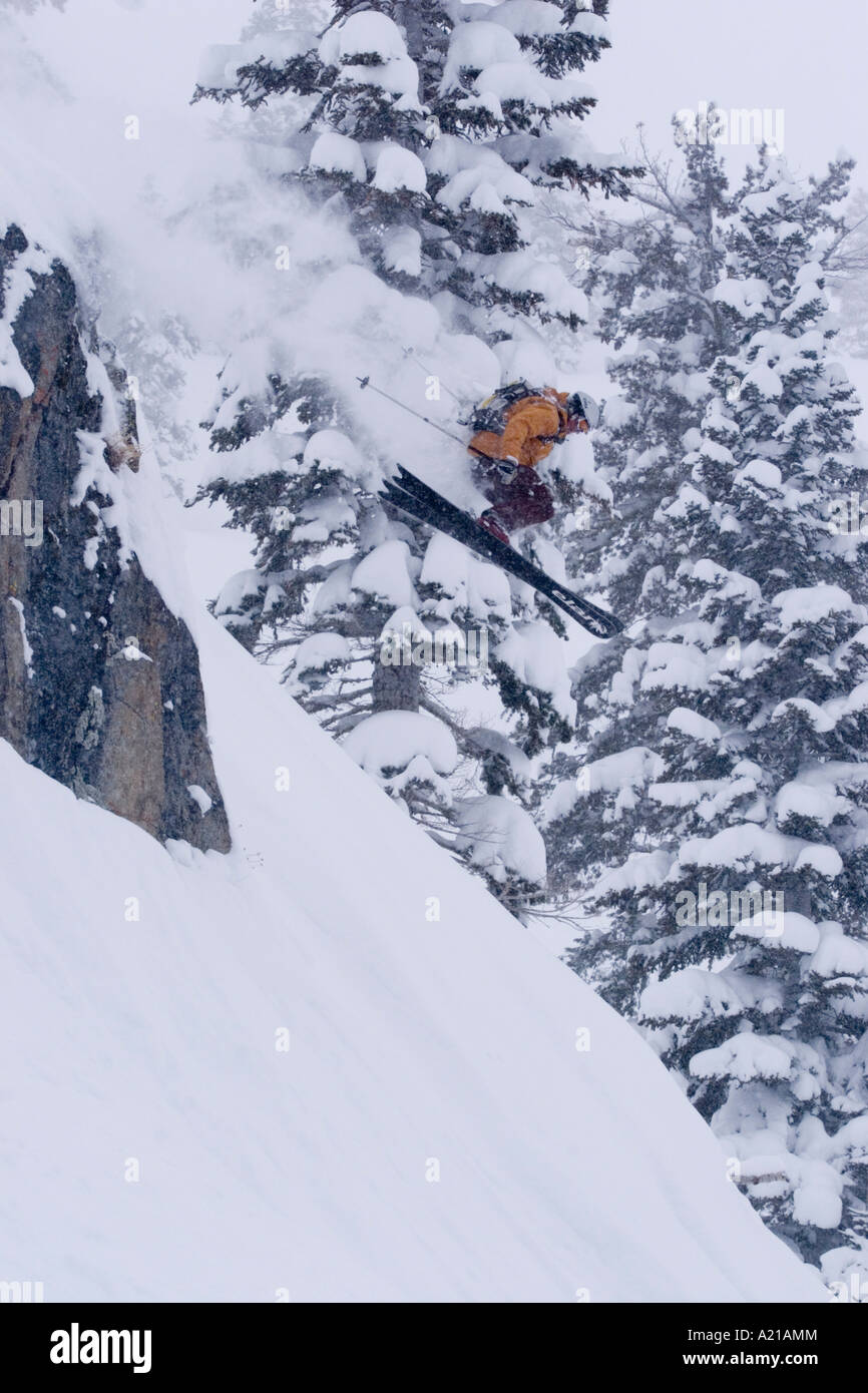A man skiing off a cliff in deep powder snow in a storm at Alpine