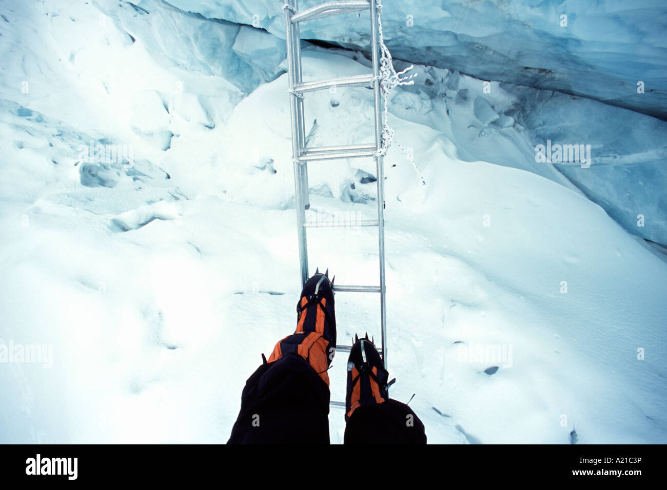 A climber on Mount Everest crossing a crevasse on a ladder in the Khumbu icefall in Nepal Stock Photo