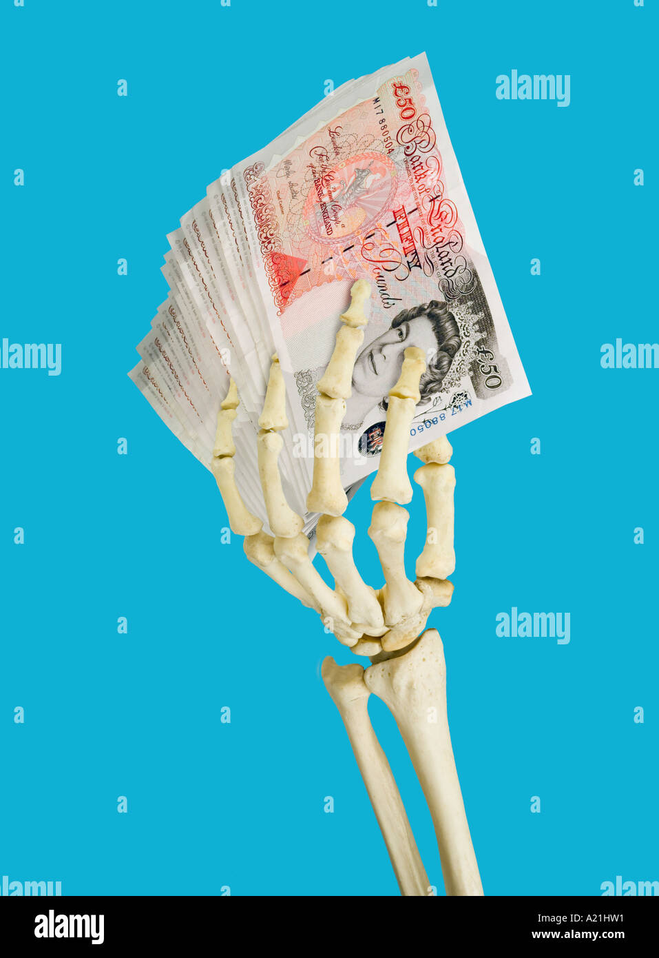 Human skeleton left hand holding British fifty 50 pound notes Stock Photo