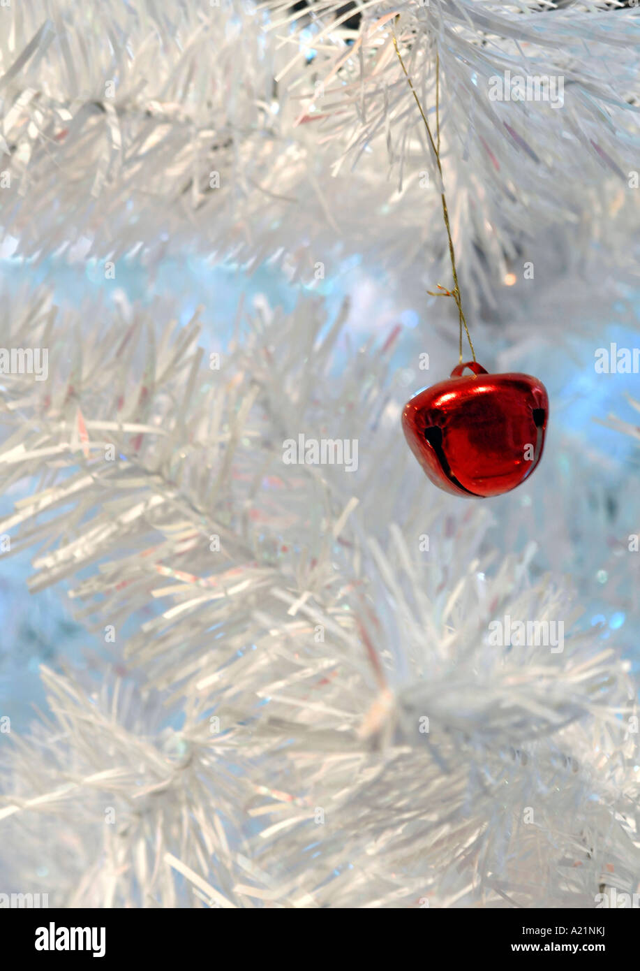 Close up shot of a single red decoration hanging on a white Christmas tree. Stock Photo
