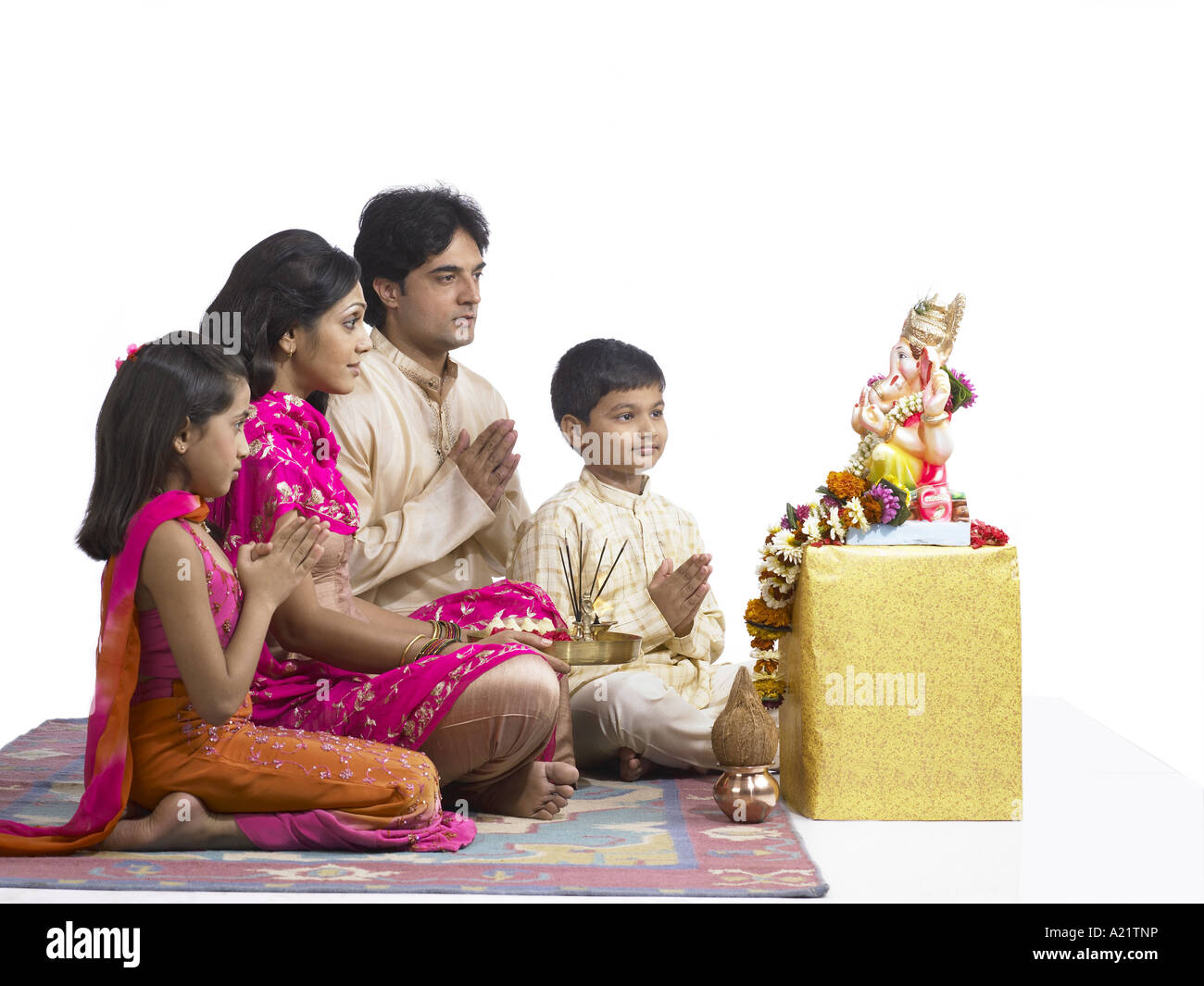 South Asian Indian family with father mother son and daughter sitting praying to lord Ganesha wearing traditional dress kurta Stock Photo