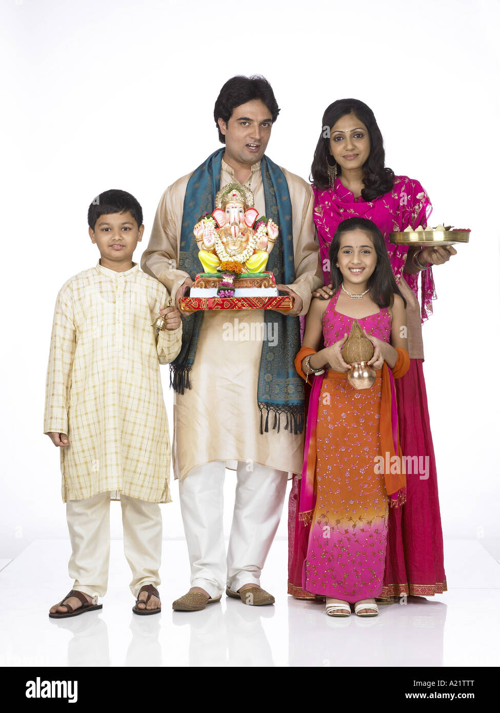 South Asian Indian family holding statue of lord Ganesha Kalash Arati thali and wearing traditional dress kurta pajama Stock Photo