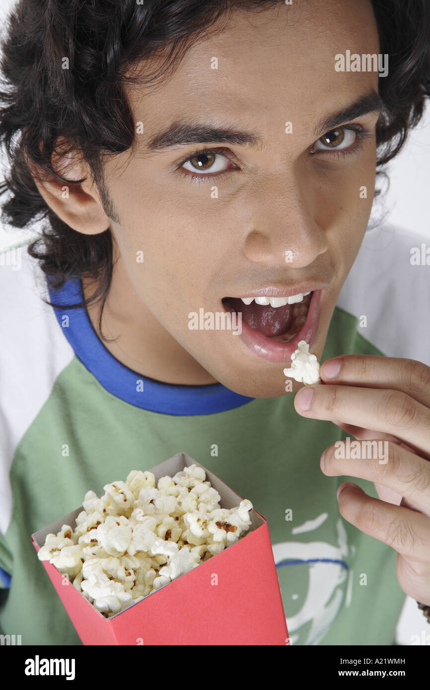ANG200441 Teenage boy holding popcorn pack in one hand and eating pop