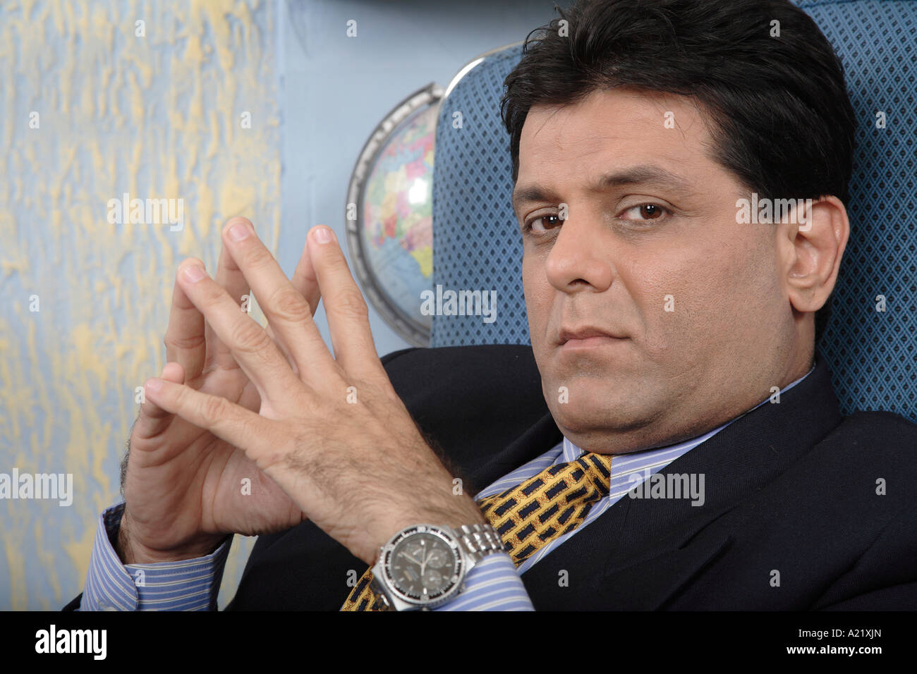 Executive Boss sitting in his cabin well established businessman both the hands joined thinking wrist watch Stock Photo