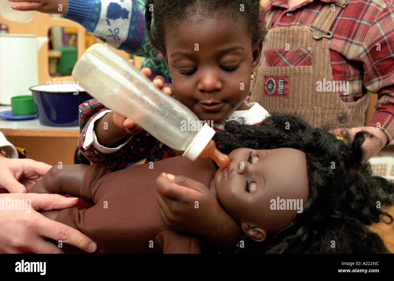 Female toddler pretending to feed a doll during role playing. UK Stock Photo