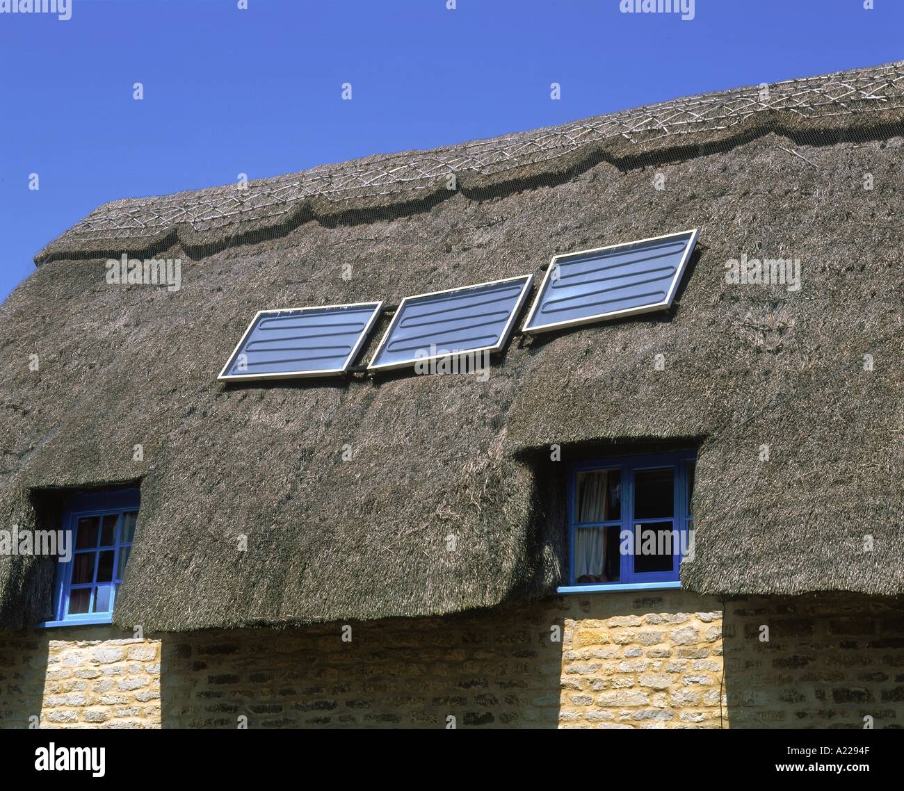 Solar water heating panels on a thatched roof N Francis Stock Photo