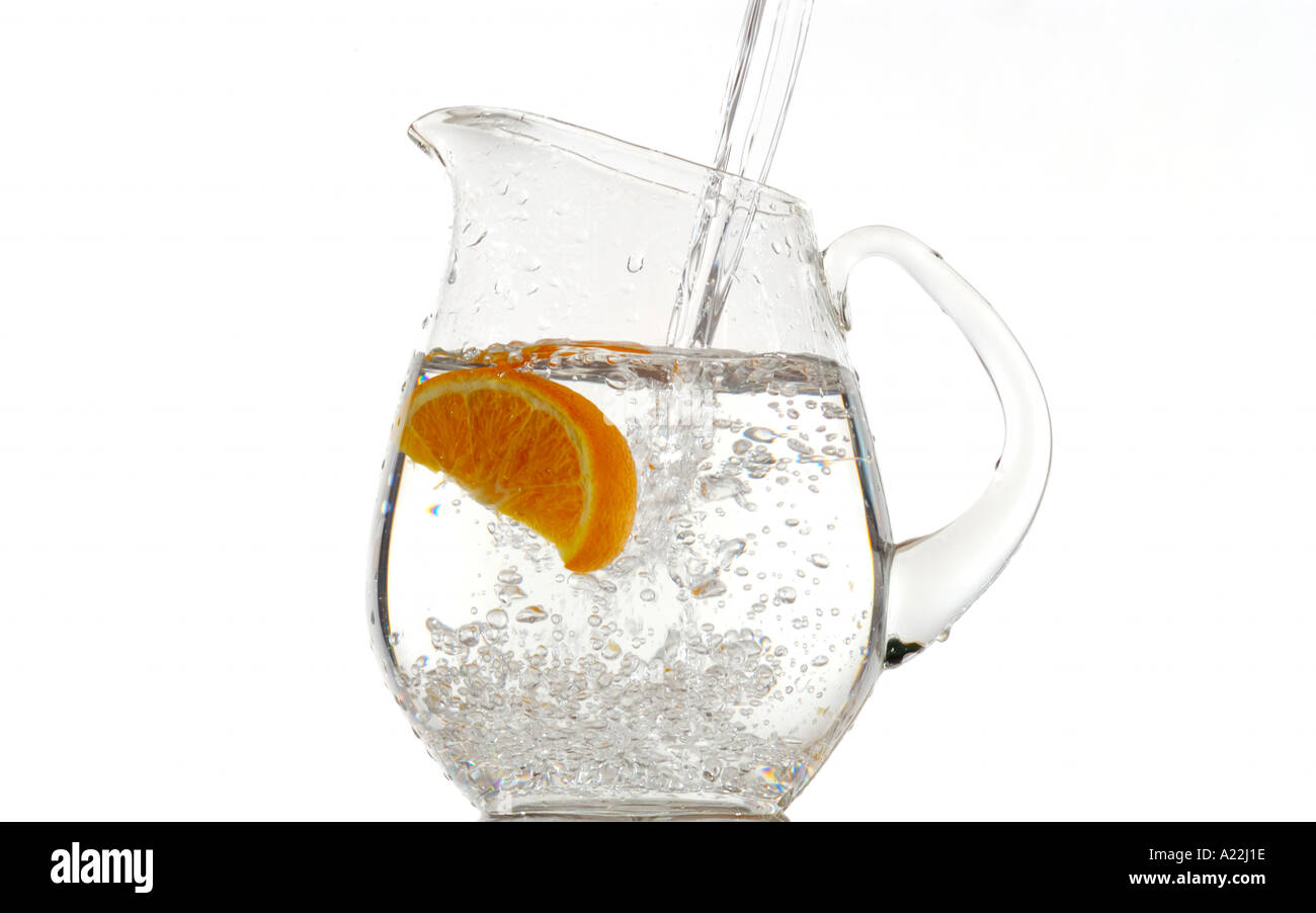 orange dropped into water pitcher Stock Photo