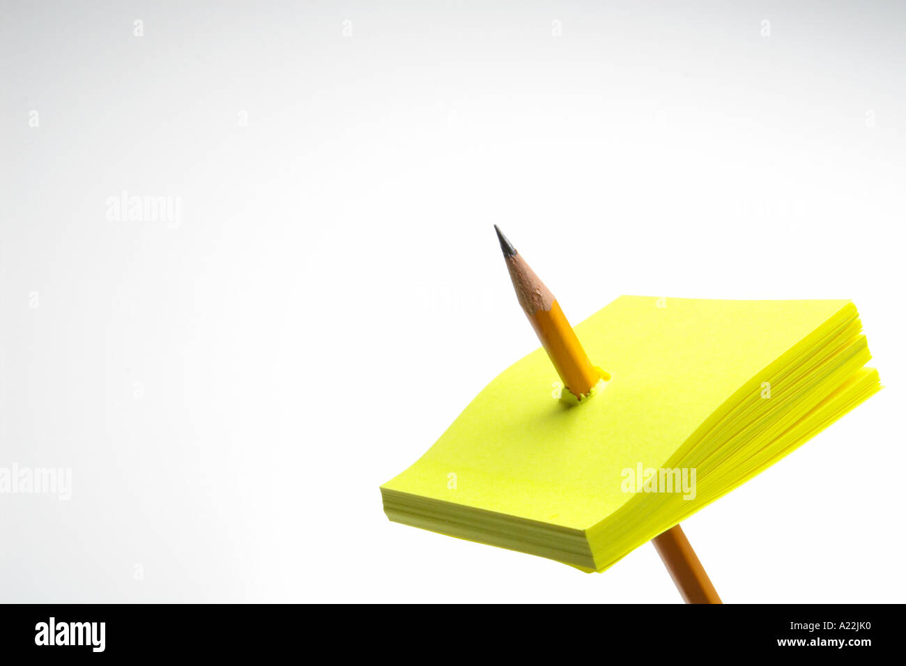 pencil punched thru yellow sticky note pad Stock Photo Alamy