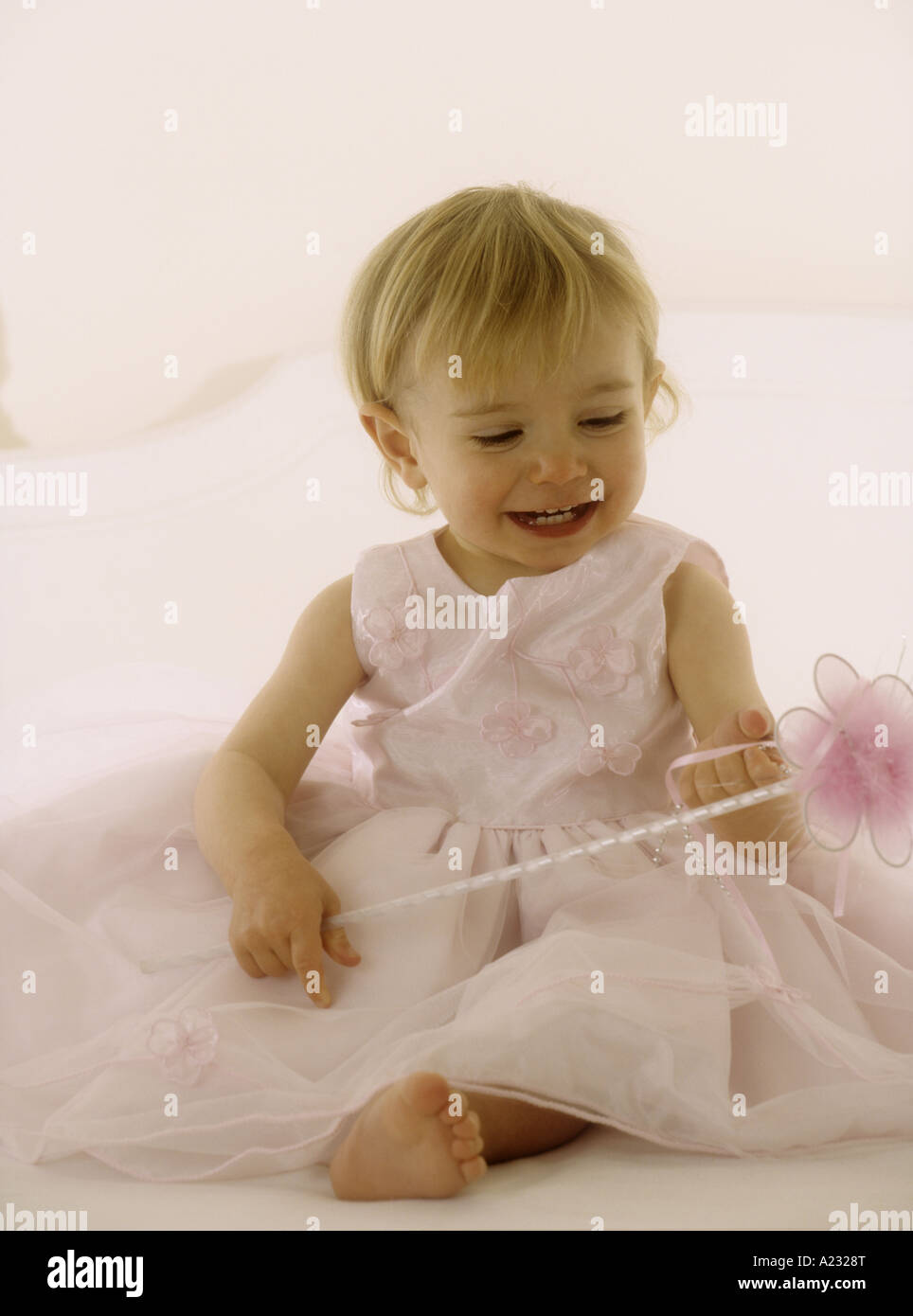 Toddler wearing a pink party dress holding a wand Stock Photo