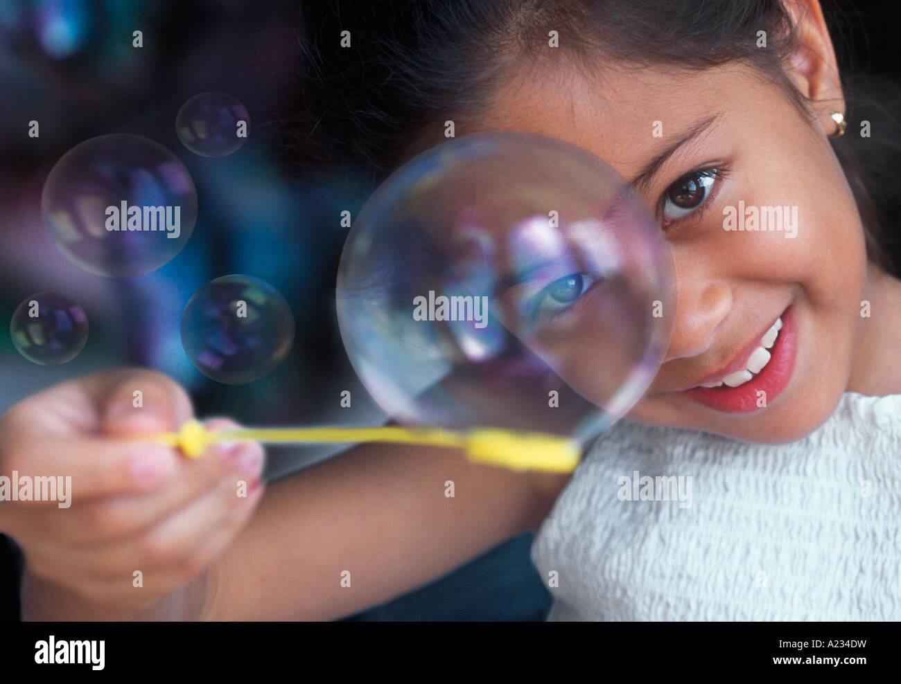 Young girl blowing bubbles. Pretty child looking at camera playing games and smiling Stock Photo
