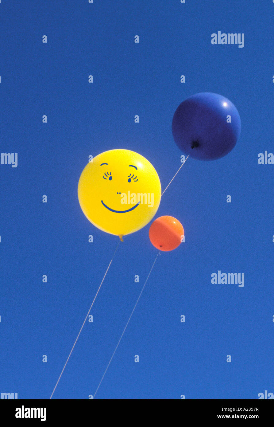 Smiley Face  balloons floating against a blue sky. Happiness. Carefree. Stock Photo