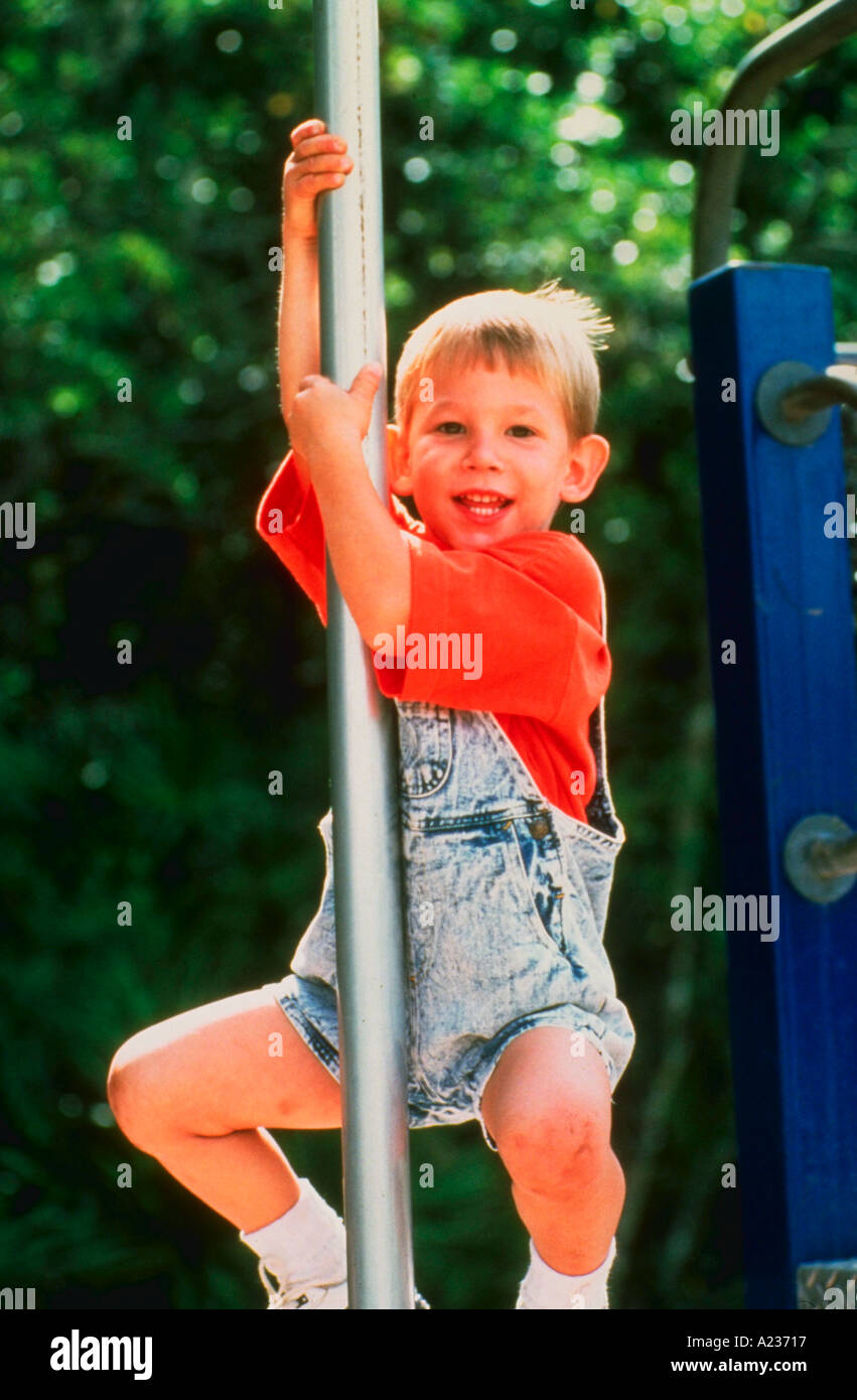 Young boy playing on bars at playground Stock Photo