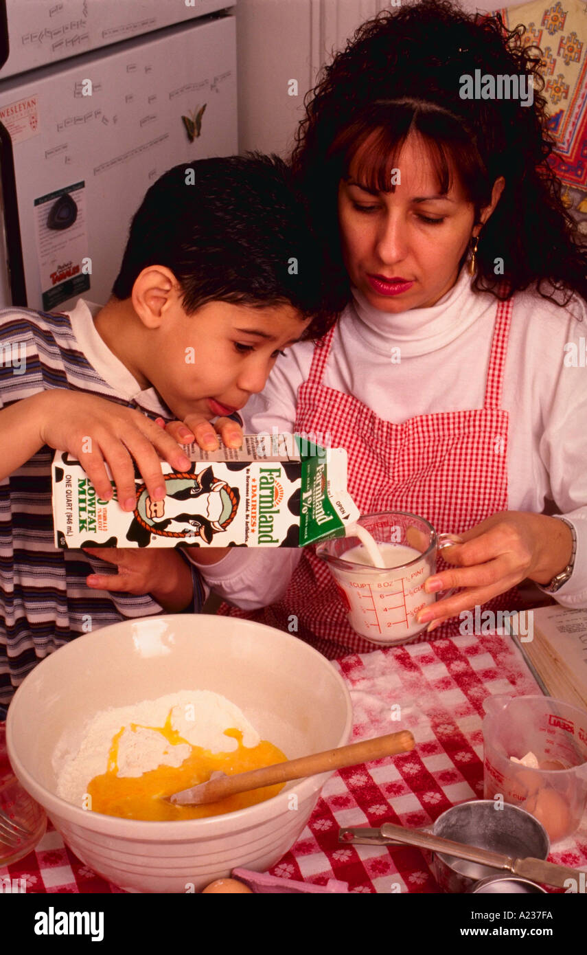 Hispanic 6 year old boy baking a cake with his mother Stock Photo