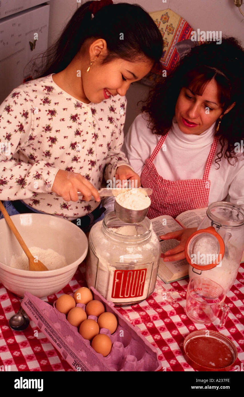 Hispanic 9 year old girl baking cake with her mother Stock Photo