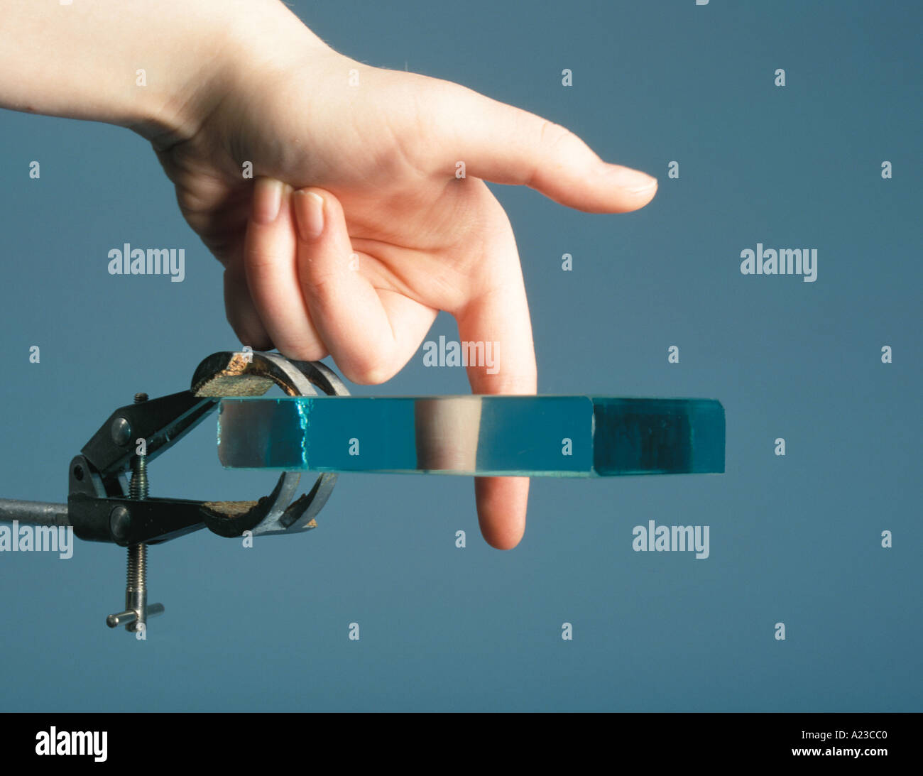 a finger appears to have a piece missing when seen through a glass block due to refraction of the light Stock Photo