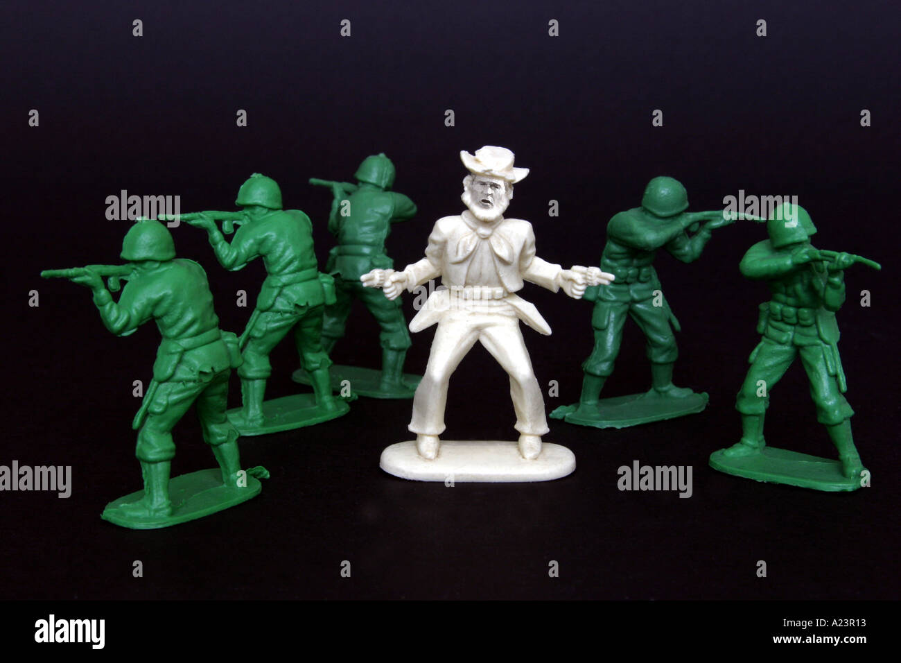 toy gunslinger cowboy with face of George W Bush surrounded by 5 plastic American soldiers pointing their guns protectively Stock Photo