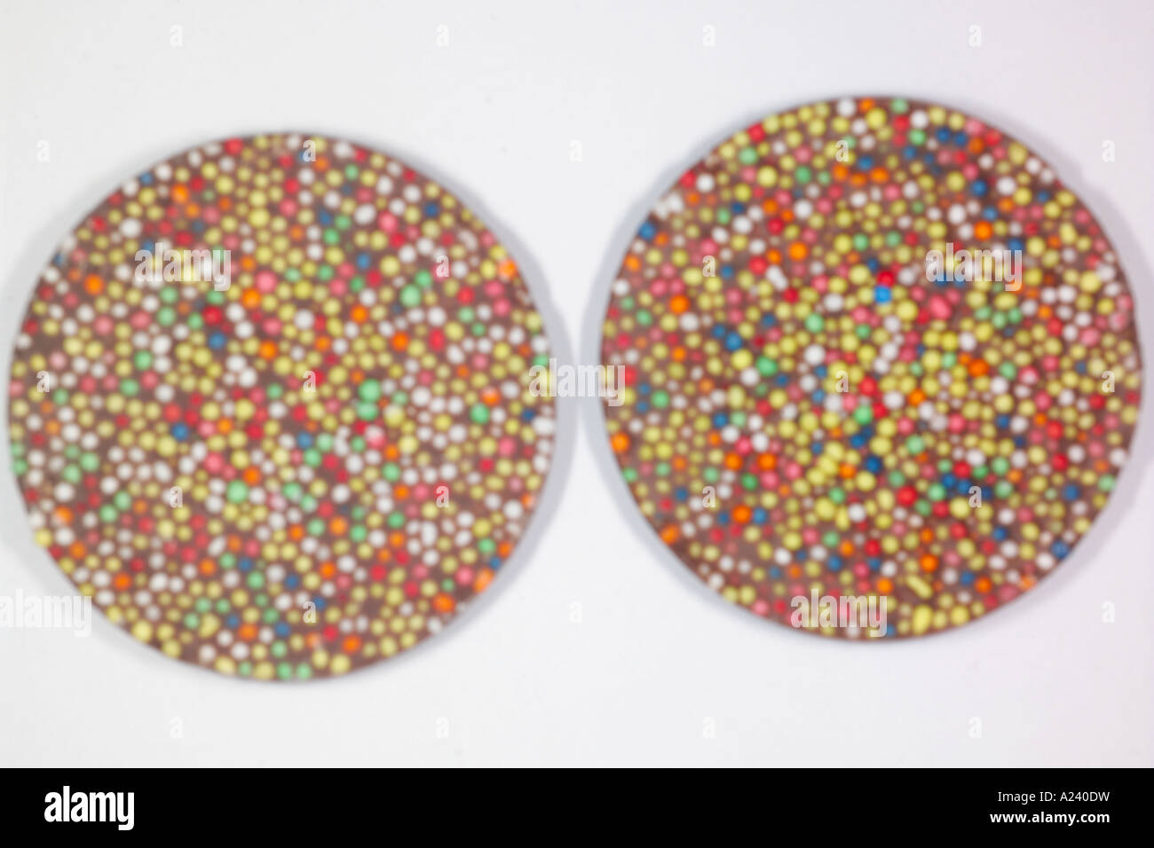 Large milk chocolate discs covered in sprinkles. Stock Photo