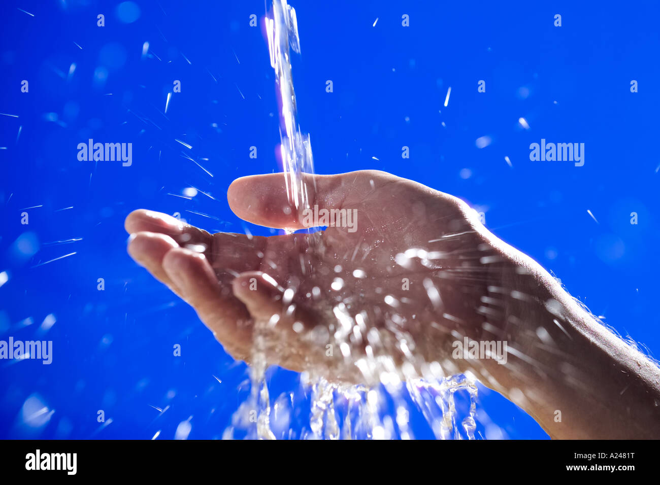 Hands splashed with running water against blue background Stock Photo ...