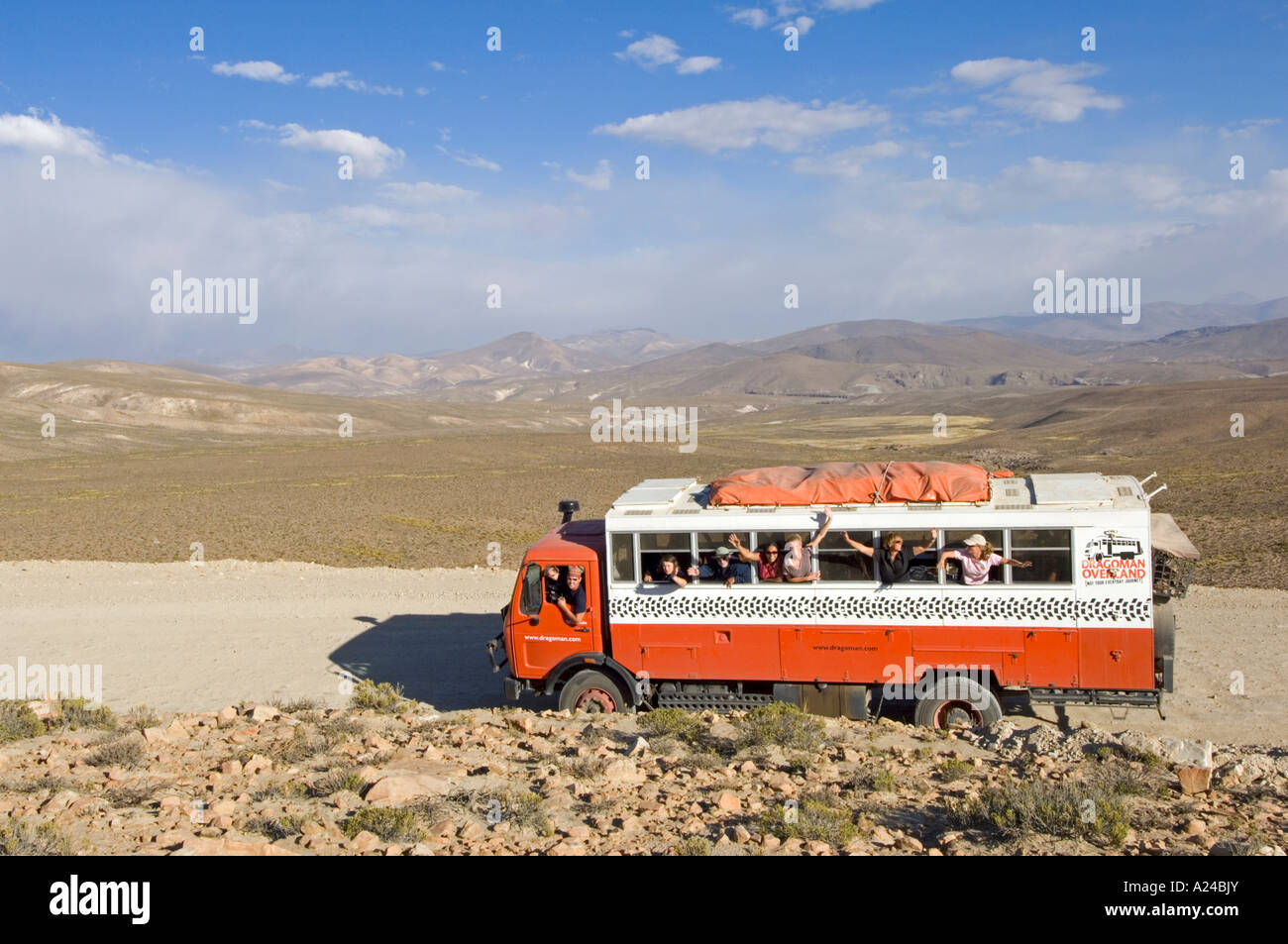 An overland adventure holiday truck travelling through the countryside of Peru with all the passengers waving from the windows. Stock Photo