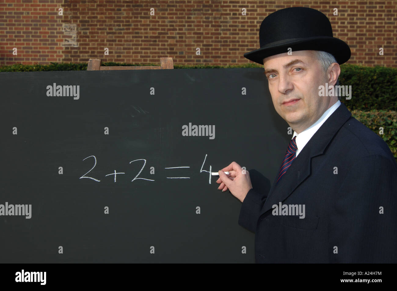 City gent accountant adding up 2+2=4 on a blackboard Stock Photo