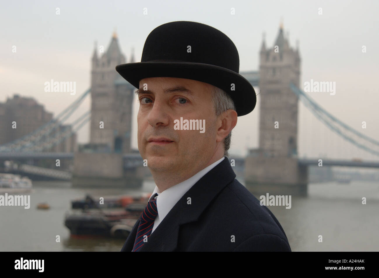 Traditional English city gent in suit and bowler hat by Tower Bridge, City of London, UK. Stock Photo