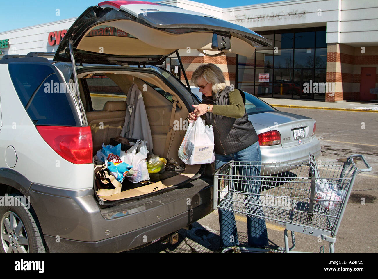 Adult female loads groceries into her car after shopping at a grocery store Stock Photo Alamy