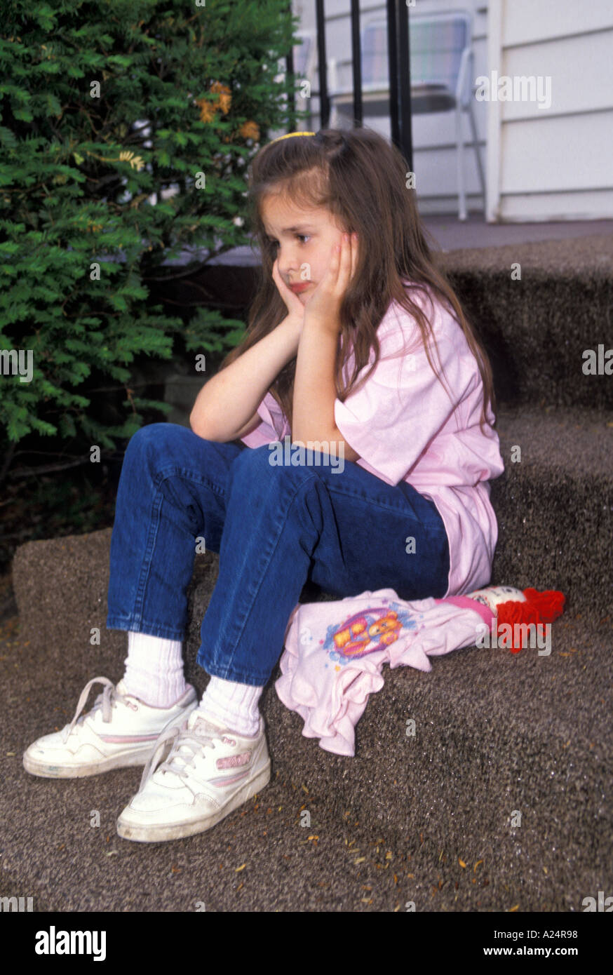 small girl student sits on steps with her head in her hands Stock Photo