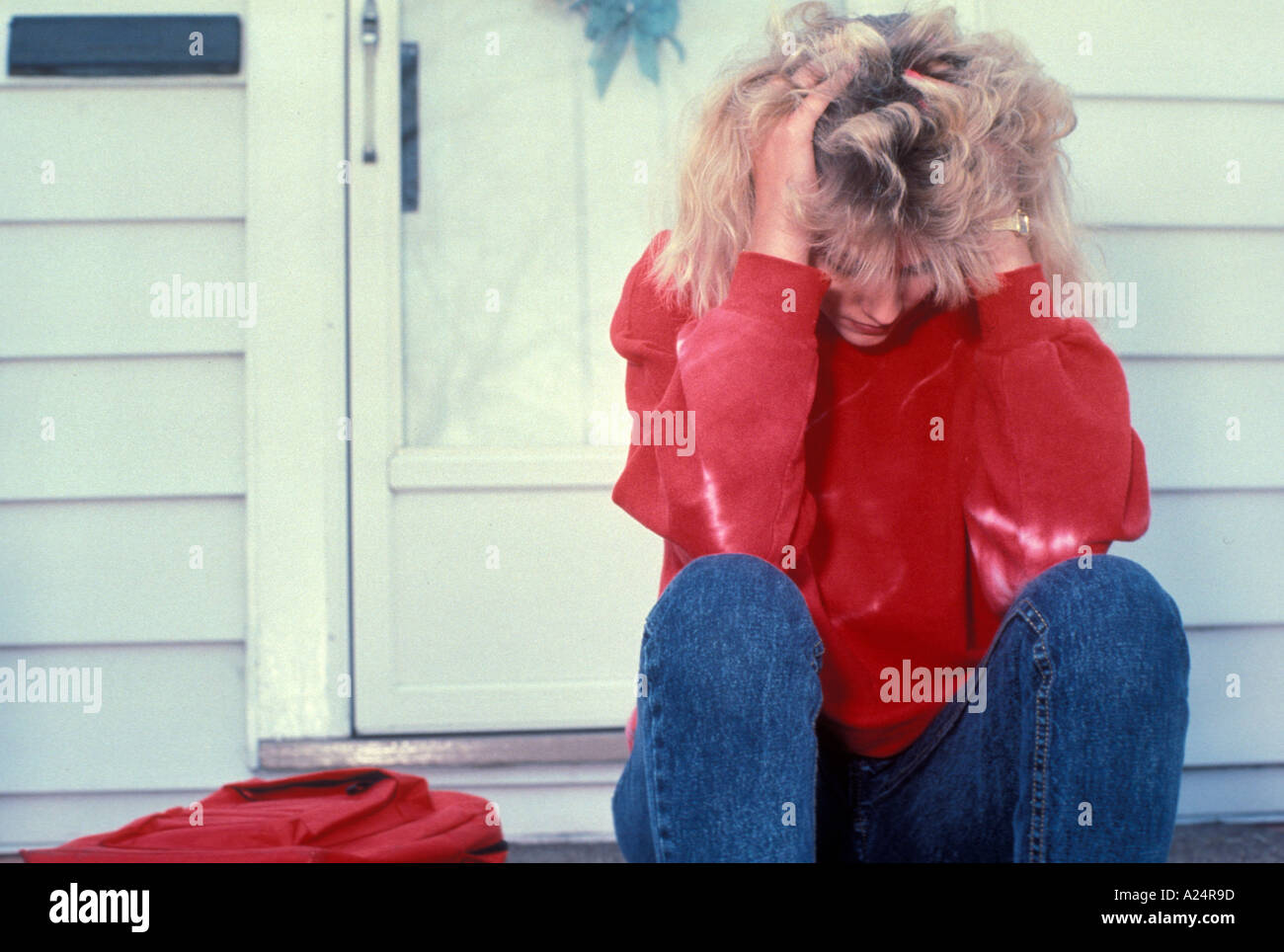 High school student sits on steps with her head in her hands Stock Photo