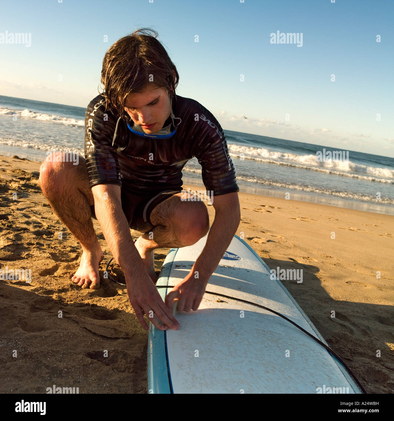 A surfer waxes his board on the Playa Bruja beach in Mazatlan Mexico Stock Photo