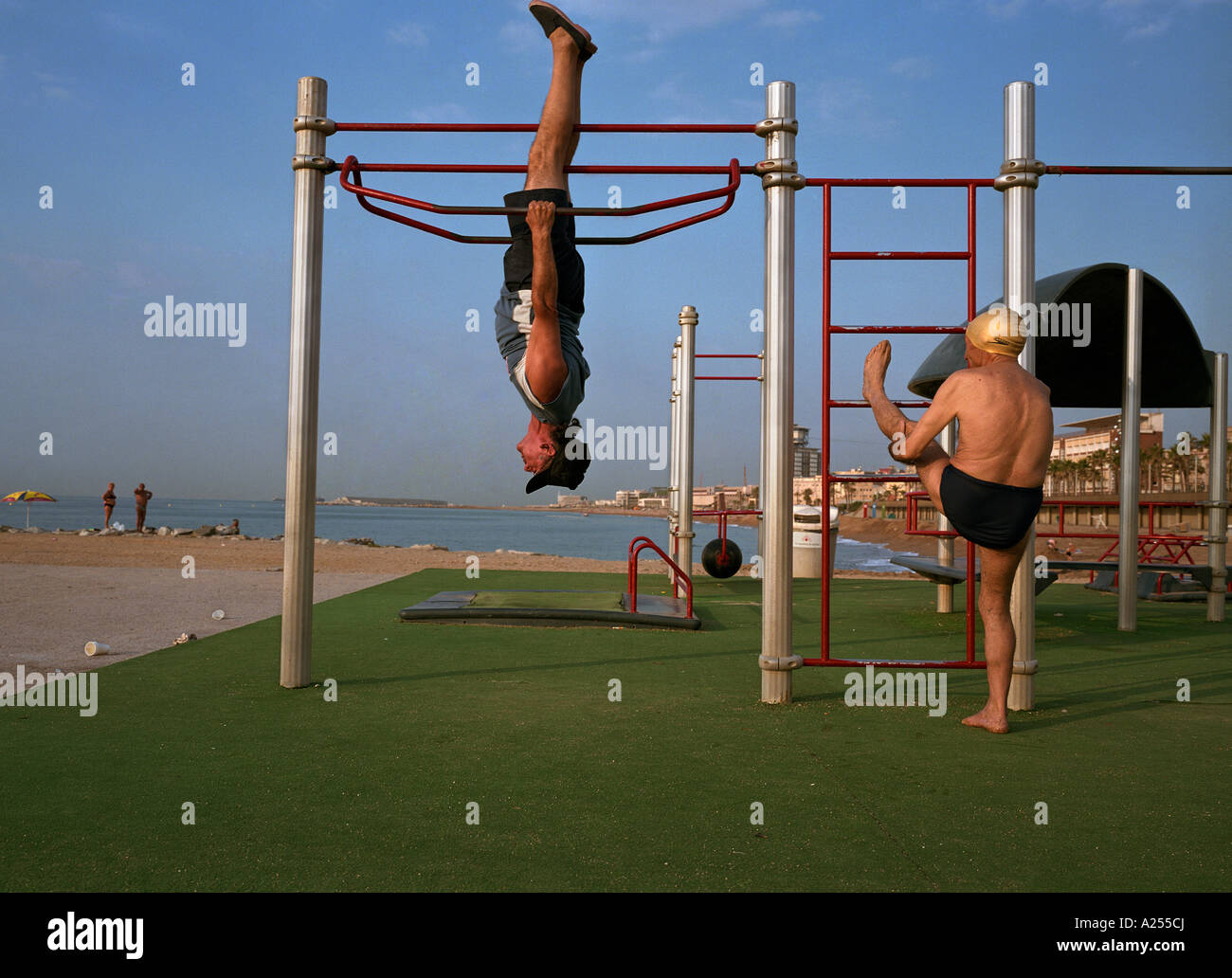 Two Spanish gentlemen exercise on the beach near Port Olympic in Barcelona Spain Stock Photo