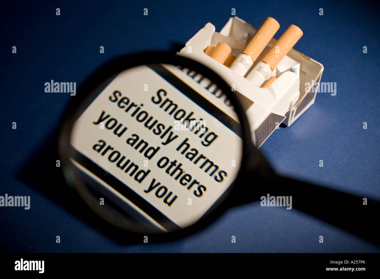 Health warning on packet of cigarettes viewed through a magnifying glass Stock Photo