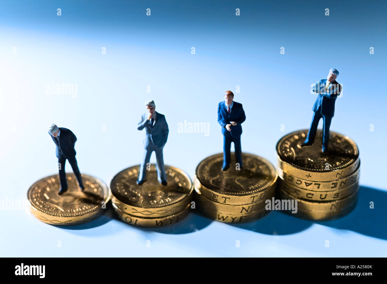 Miniature businessmen standing on coins This photo illustrates the differences in the pay scale within a company Stock Photo