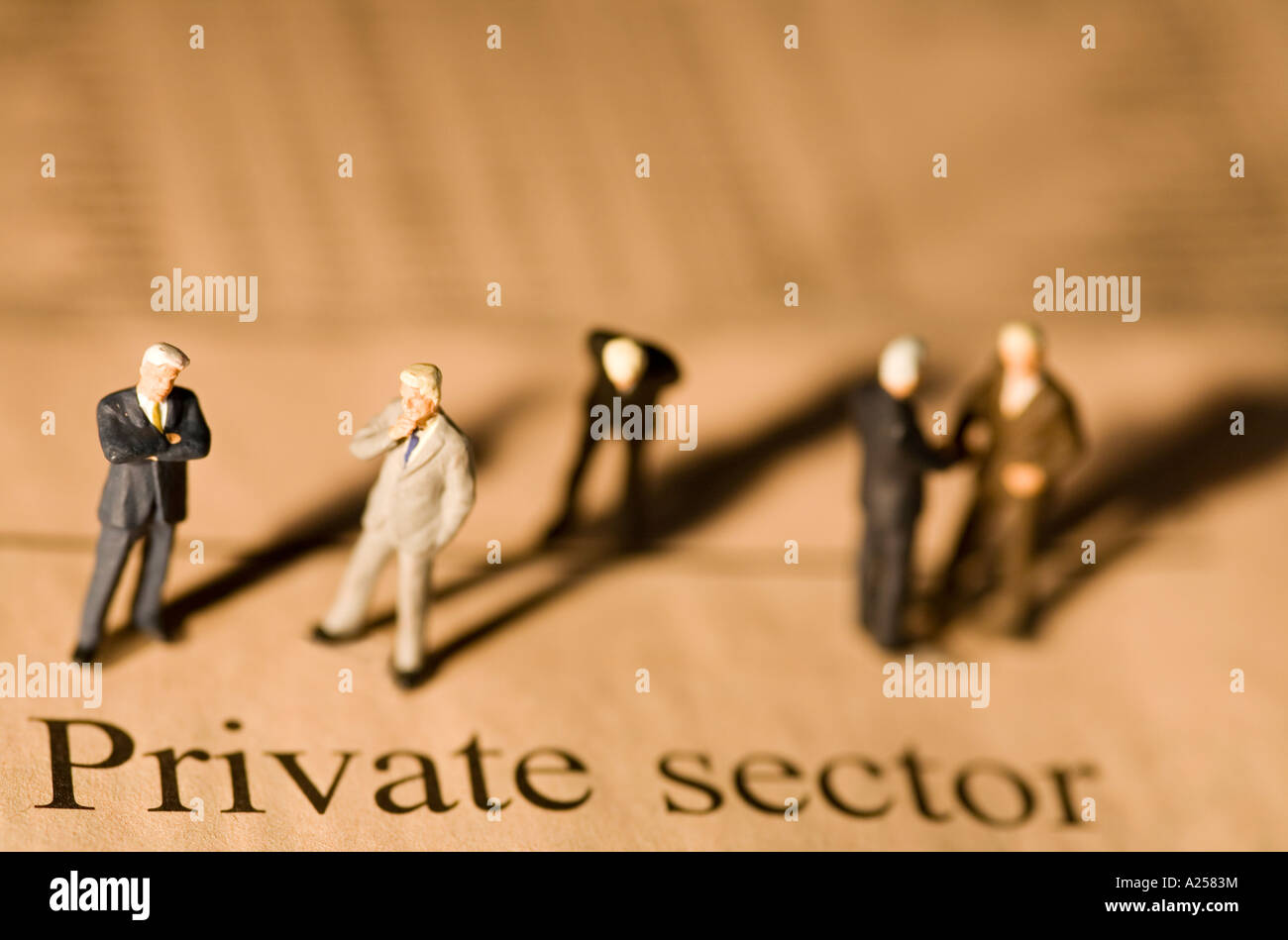 Miniature businessmen standing on financial newspaper in front of private sector headline Stock Photo