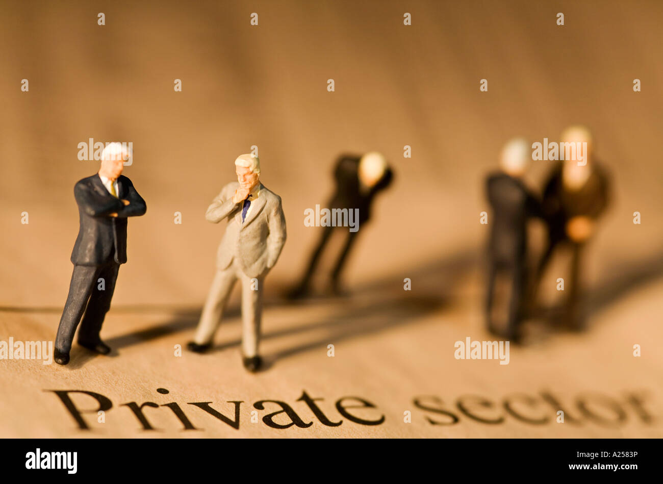 Miniature businessmen standing on financial newspaper in front private sector headline Stock Photo