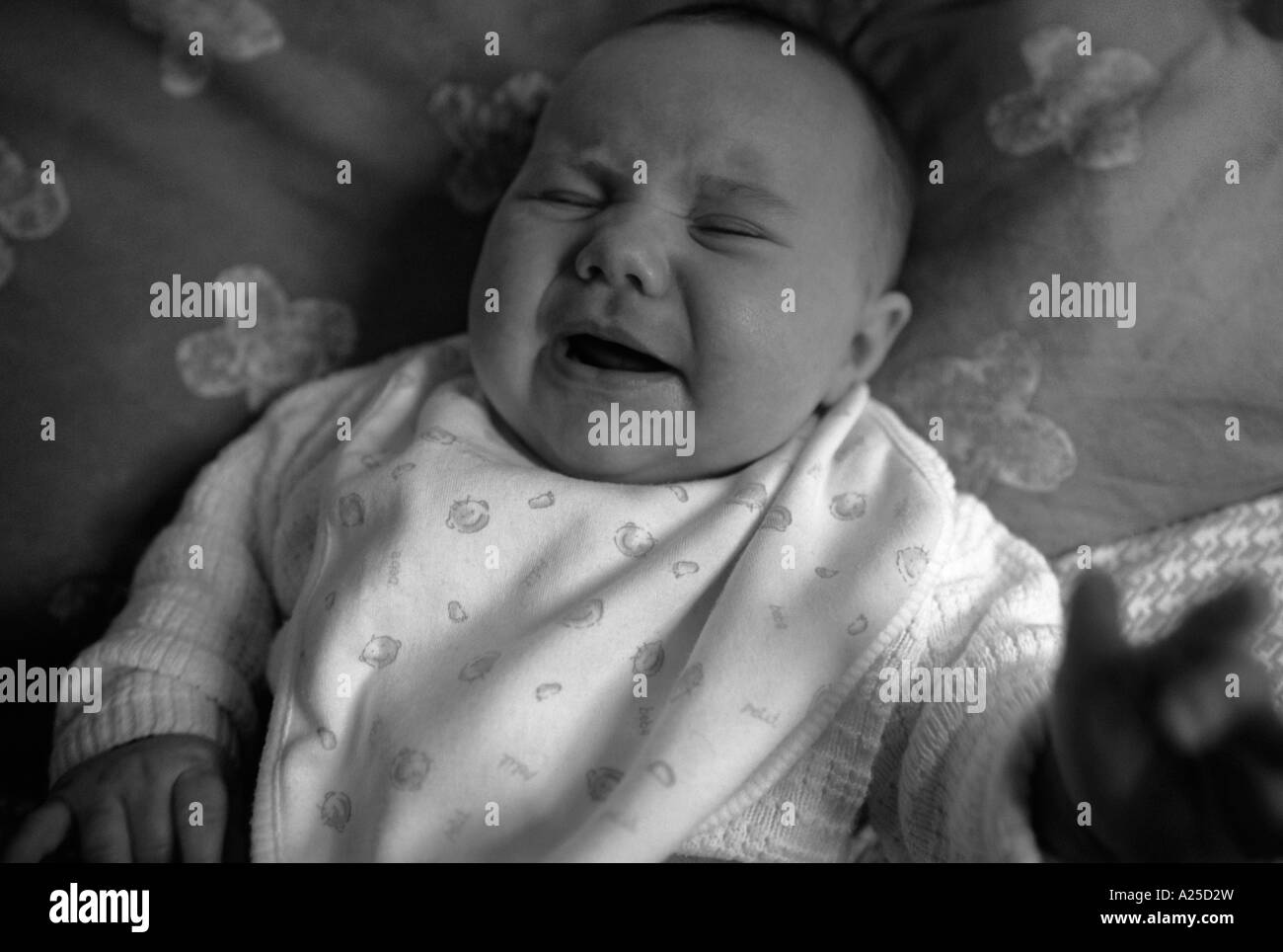 Baby lying on a bed crying Stock Photo